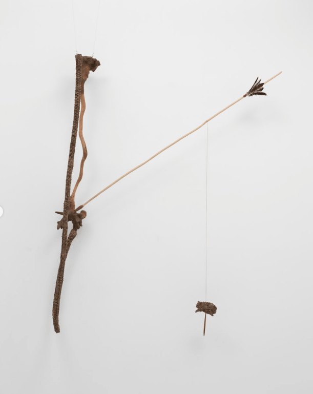 Escultura em forma de arco e flecha feita com cipó e madeira