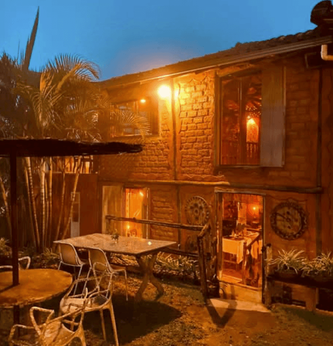 Área externa do restaurante com mesas e palmeiras